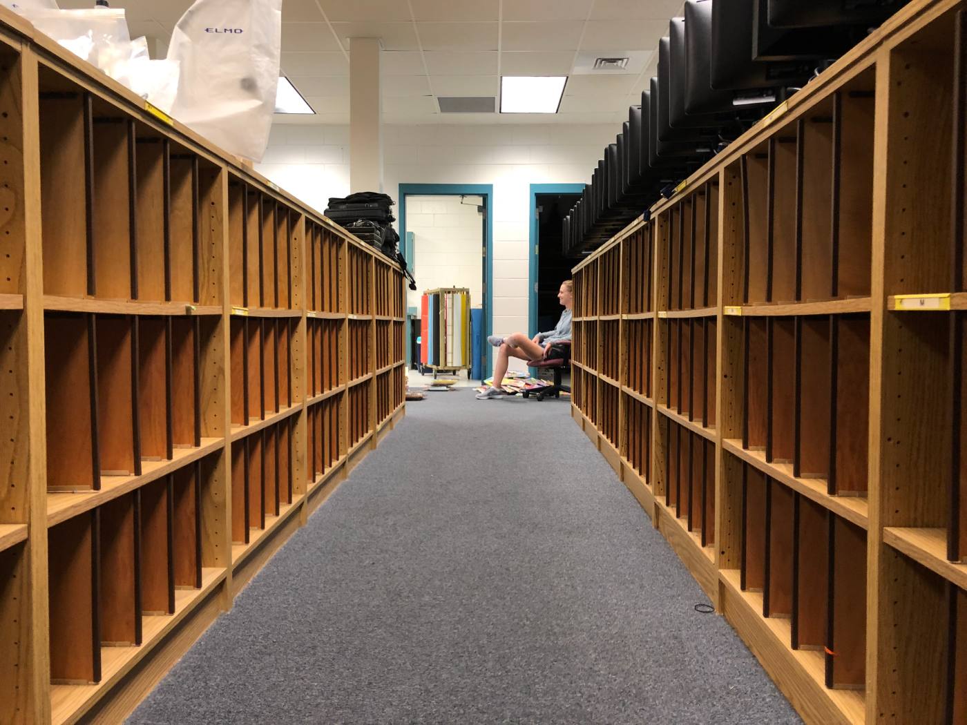 An aisle of completely empty wooden shelves running toward the workroom door.