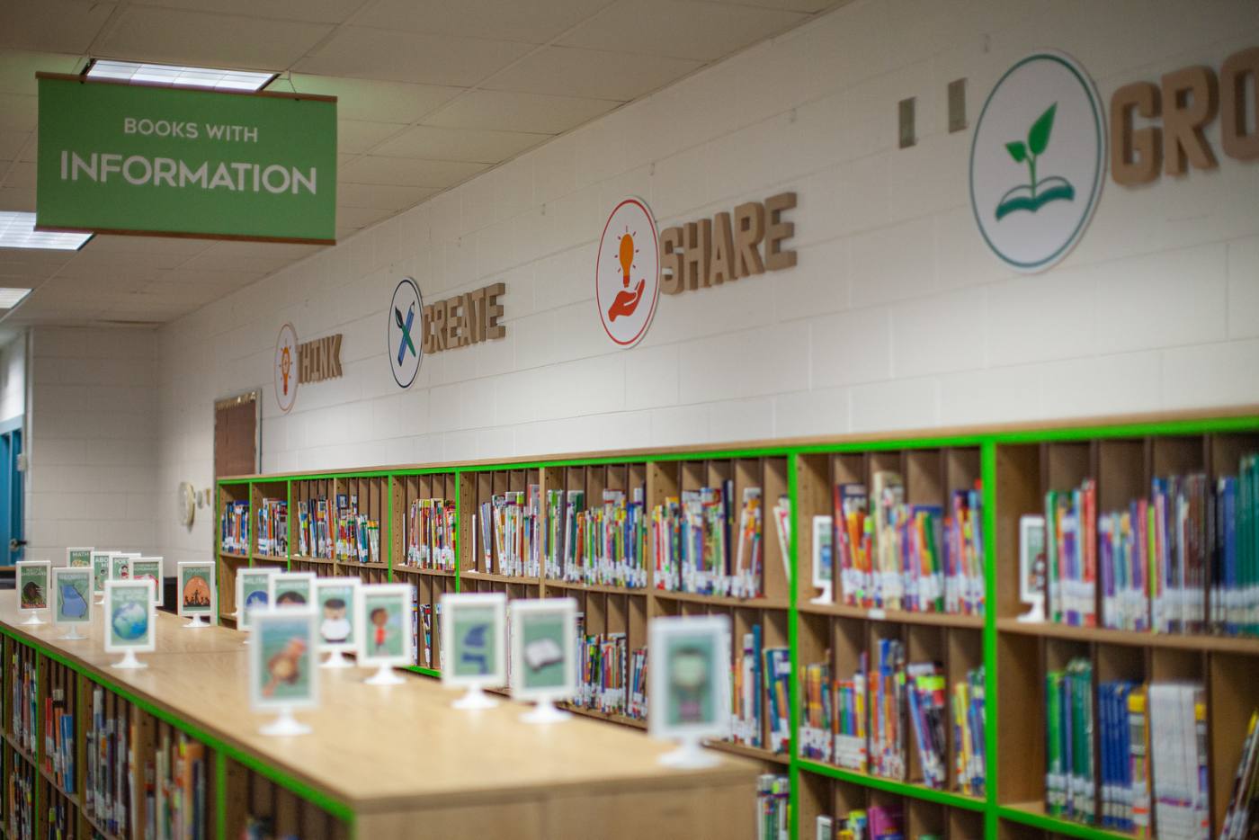 The information section: a green hanging banner, shelves edged in green, and framed genre signs along the shelf tops.