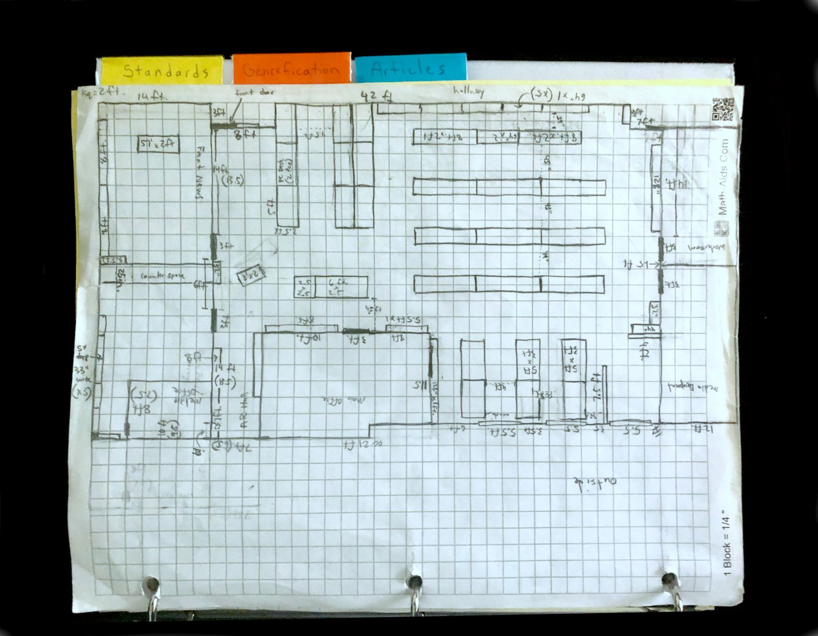 The Satilla Marsh Elementary library drawn by hand to scale on graph paper, in a binder with tabs for Standards, Genrefication, and Articles. Every wall, door, shelving run, and aisle is measured in feet and inches.