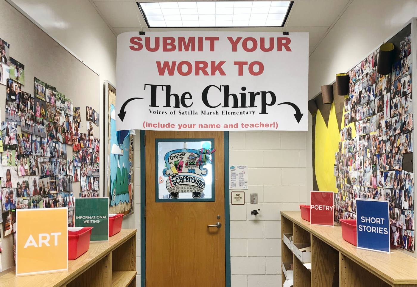 A hallway alcove under a banner reading Submit Your Work to The Chirp, with red bins labeled Art, Informational Writing, Poetry, and Short Stories.