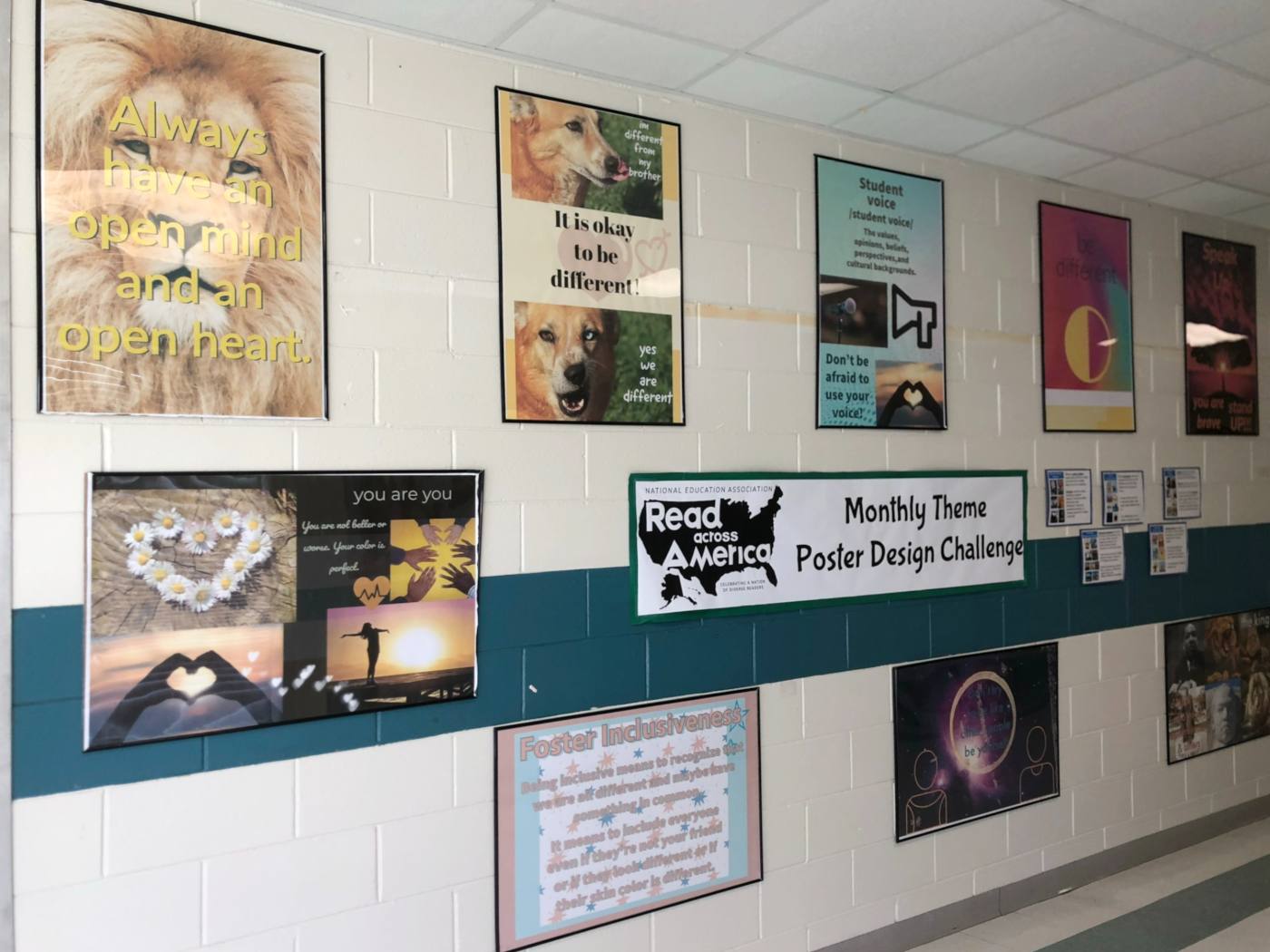 A second run of student posters on the same wall, a lion poster reading Always have an open mind and an open heart at the left.